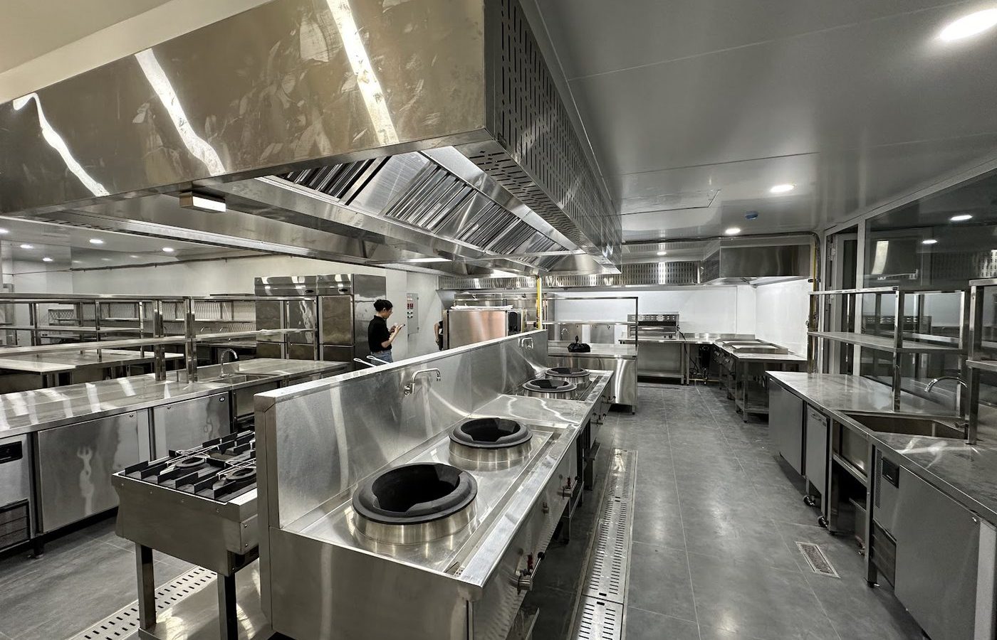 Tuyến bếp xào wok công nghiệp inox Hà Tiên với bàn lạnh và kệ inox trong khu bếp nhà hàng mới