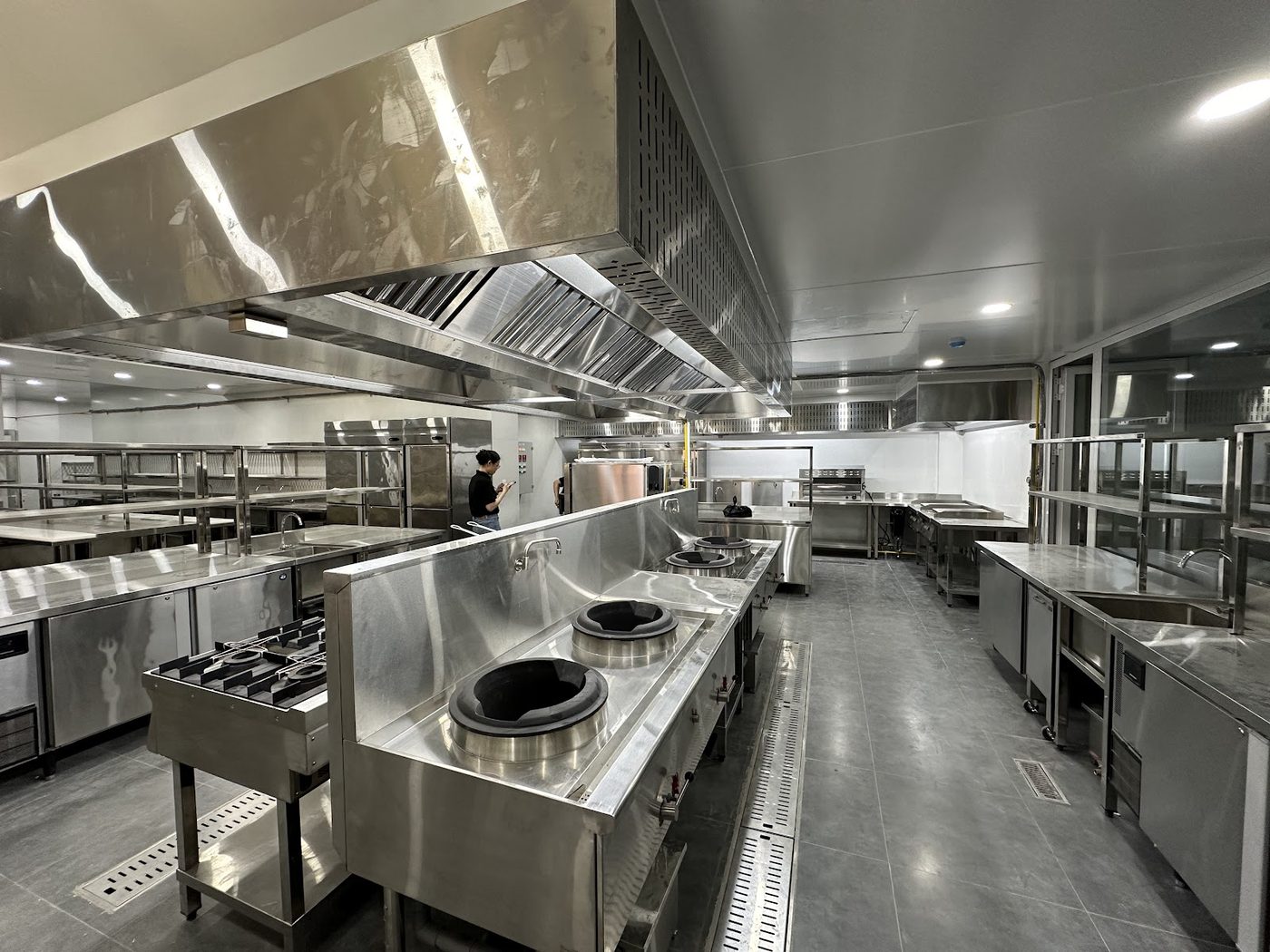 Tuyến bếp xào wok công nghiệp inox Hà Tiên với bàn lạnh và kệ inox trong khu bếp nhà hàng mới
