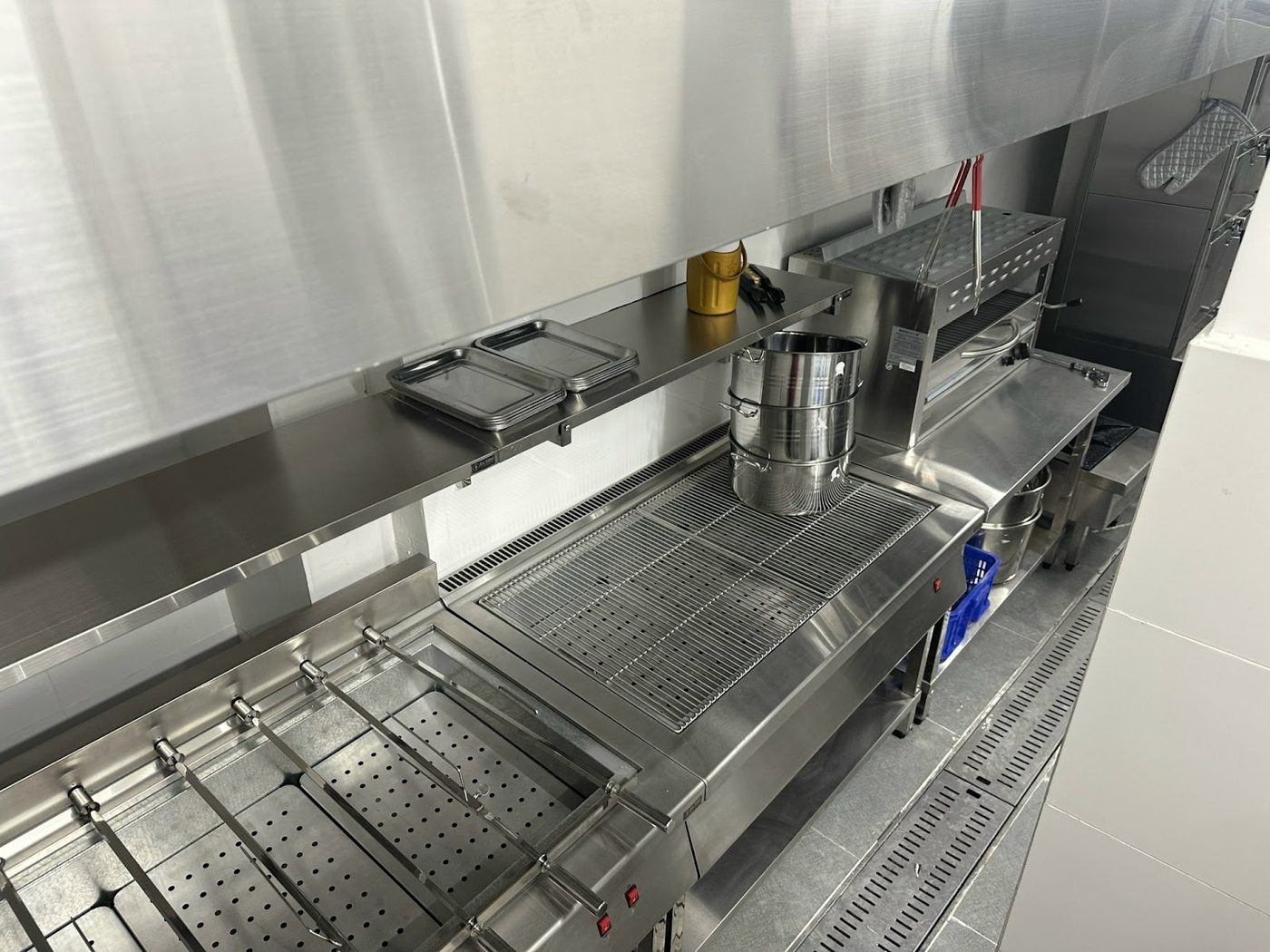 Cận cảnh bếp nướng xiên que inox, xửng hấp và lò salamander dưới hood tại nhà hàng tiệc Hương Lúa