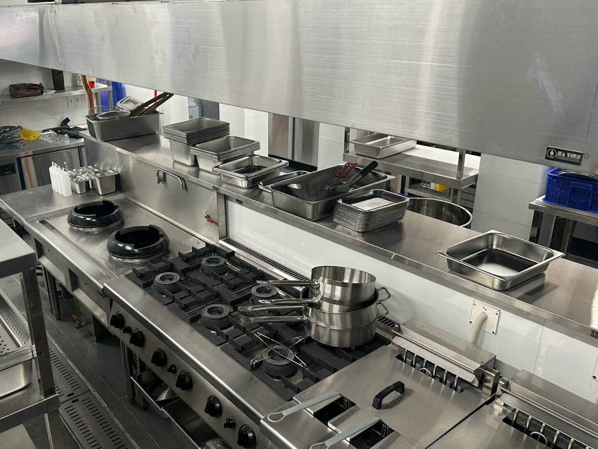 Dây chuyền bếp inox với bếp wok, bếp âu và cặp bếp chiên nhúng đôi dưới hood tại nhà hàng tiệc Hương Lúa