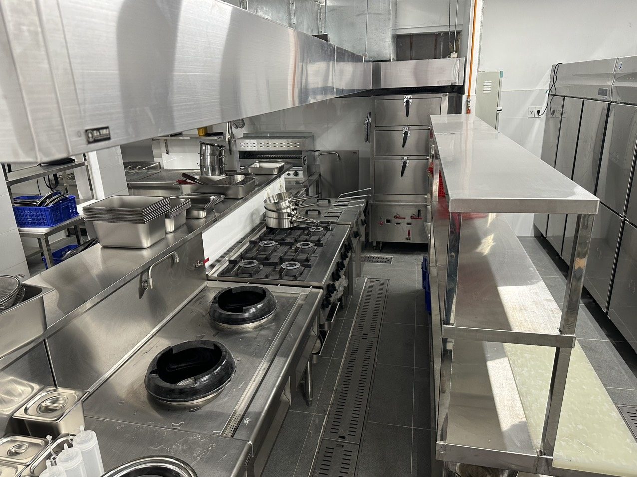 Dãy bếp xào wok đặt đối diện bếp Âu 4 họng và tủ hấp trong khu bếp nhà hàng do Hà Tiên lắp đặt