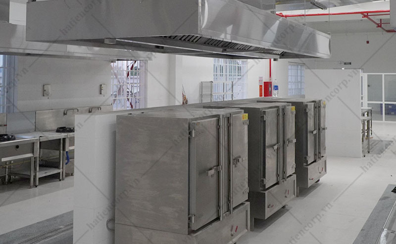 Dãy tủ nấu cơm công nghiệp đặt dưới chụp hút trong bếp ăn tập thể