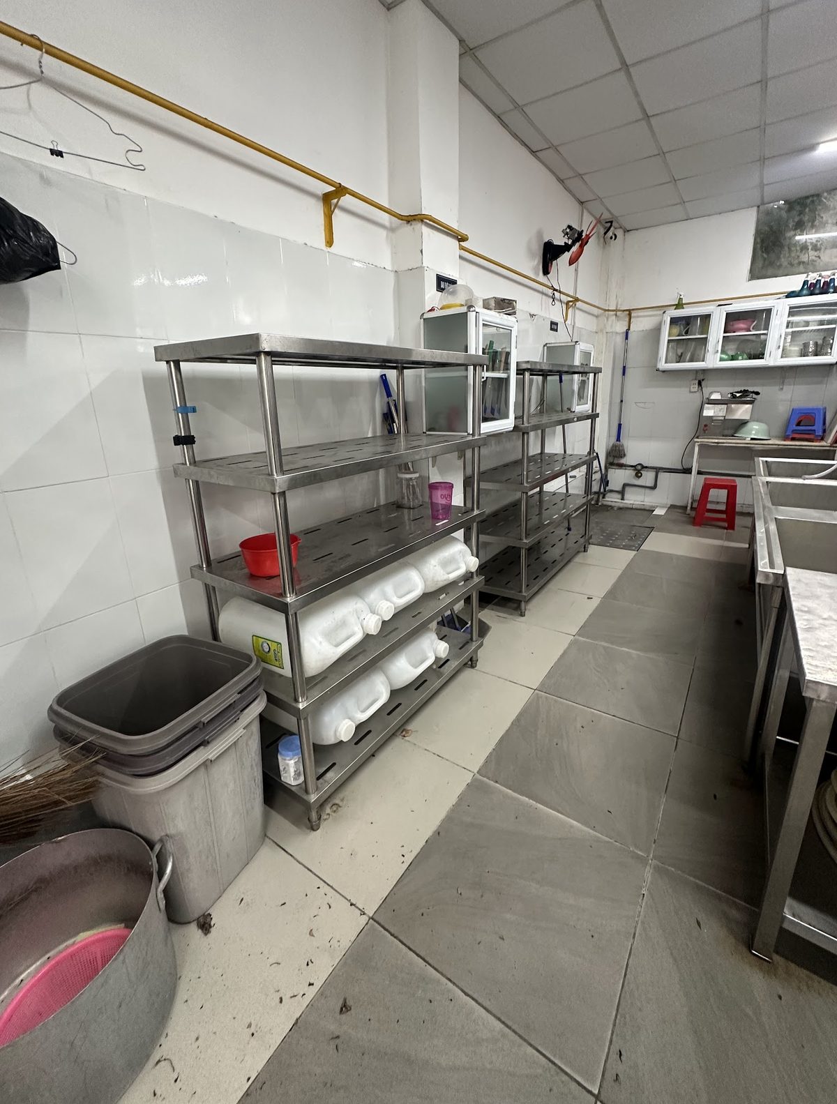 Hiện trạng một bếp trường học trước khi nâng cấp, kệ inox và thùng rác đặt sát nhau
