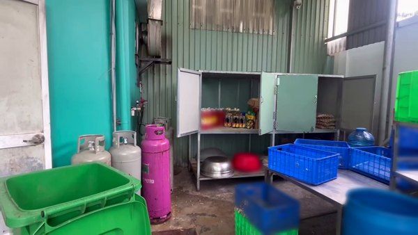 Khu phụ trợ bếp ăn công nghiệp: tủ gia vị, bình gas và thùng rác đặt chung một góc ngoài trời