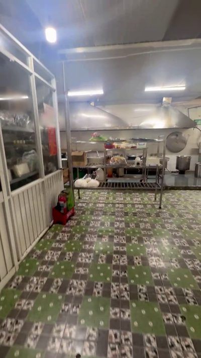 Khu nấu bếp ăn công nghiệp với dãy thiết bị nhiệt và chụp hút khói phía sau